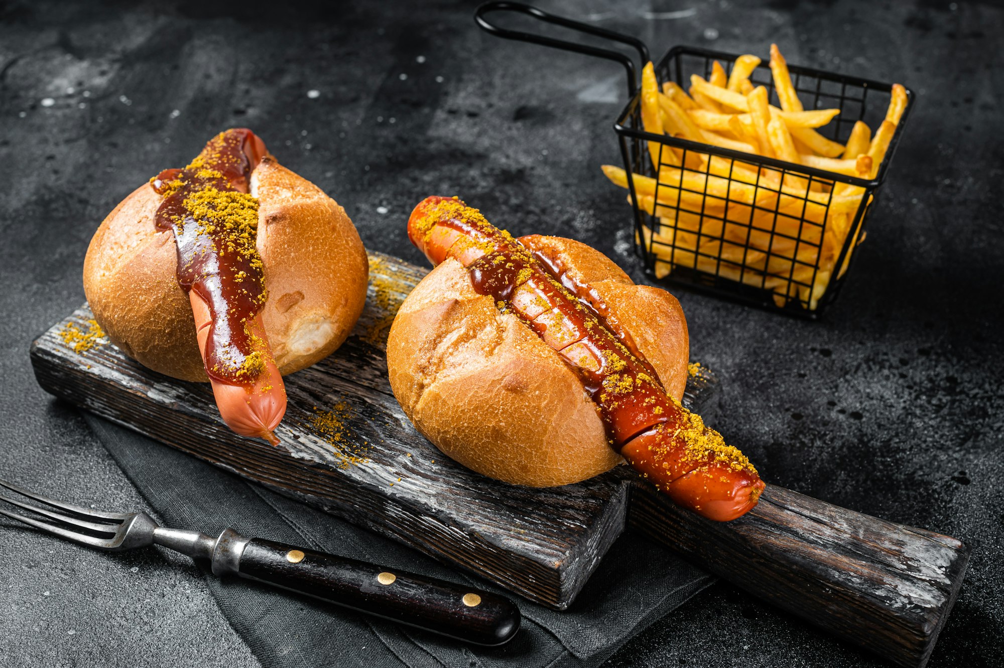 Deutsche Bockwurst sausage in a bun with French fries and curry sauce, currywurst.